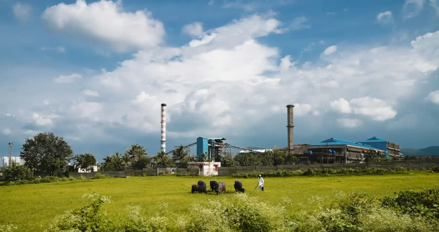 Industrial plant with chimneys beside green fields